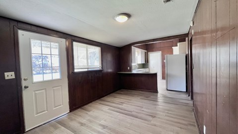 an empty kitchen with wooden cabinets and a white door