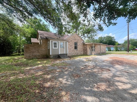 A house with a gravel driveway and trees in the background.