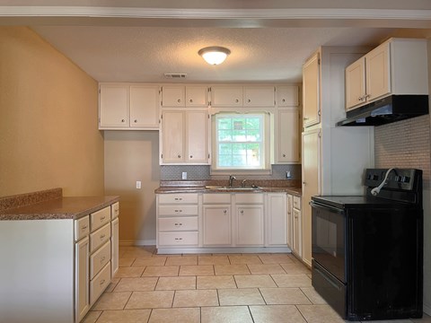 A kitchen with a black oven and white cabinets.
