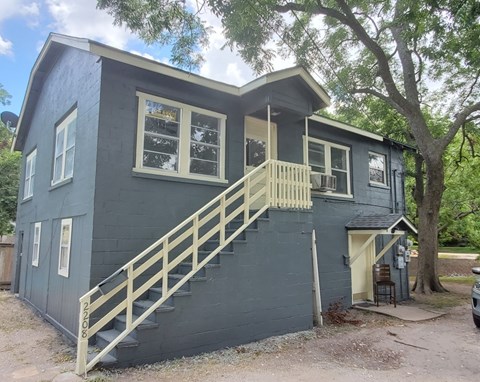 A house with a grey exterior and a wooden staircase leading to the second floor.