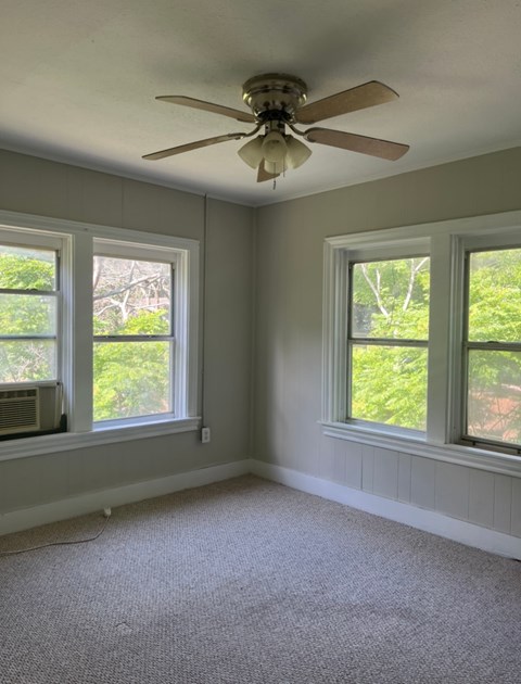 a living room with a ceiling fan and three windows