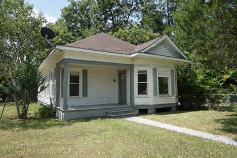 a small white house with a yard and trees