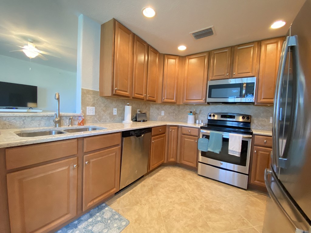 a large kitchen with stainless steel appliances and wooden cabinets
