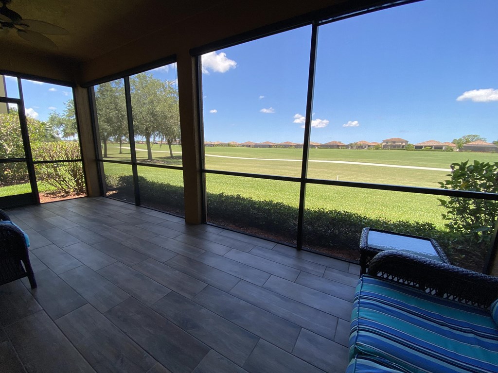 a large screened porch with a view of the field and a blue couch