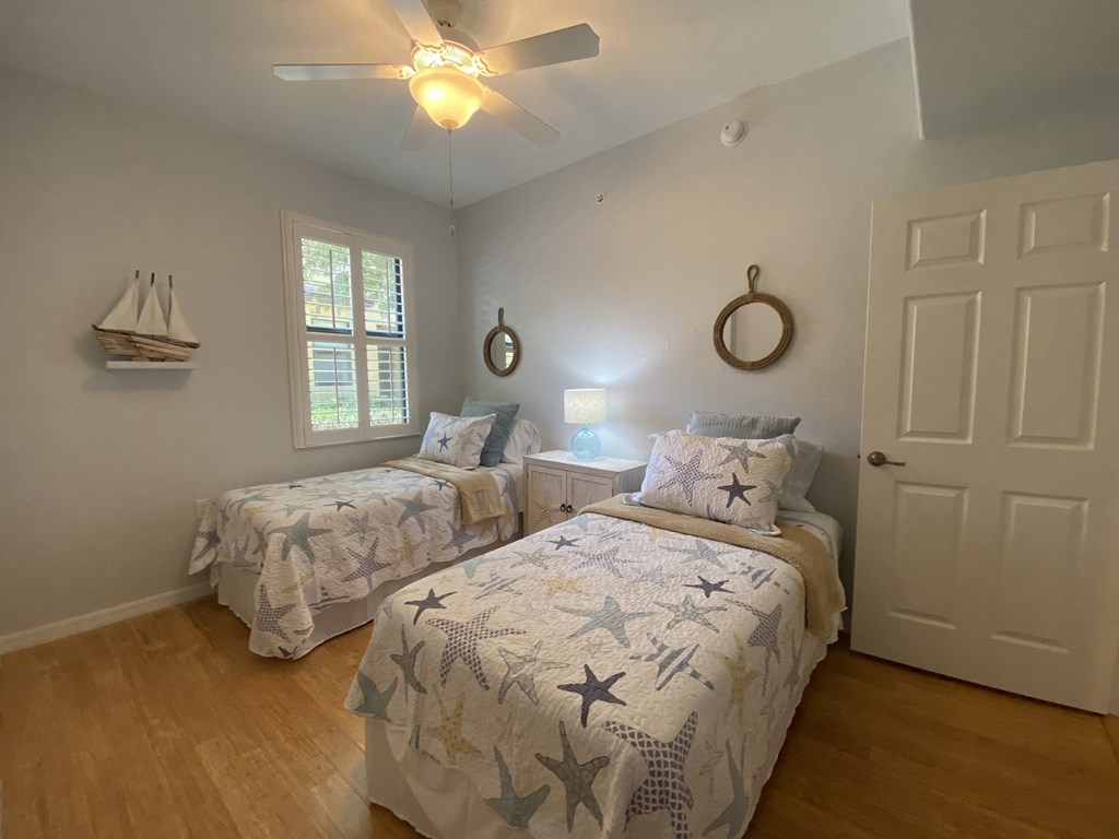 two twin beds in a bedroom with a ceiling fan and a window