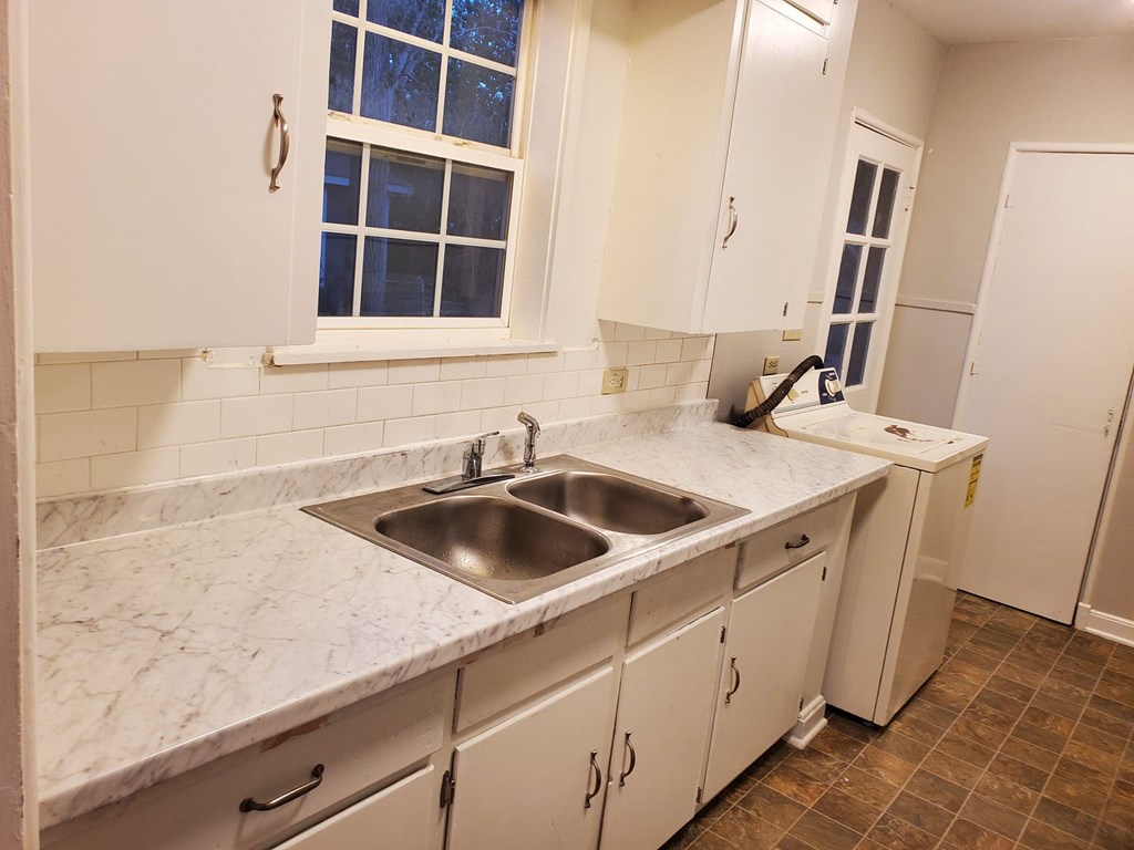 A kitchen with white cabinets and a marble countertop.