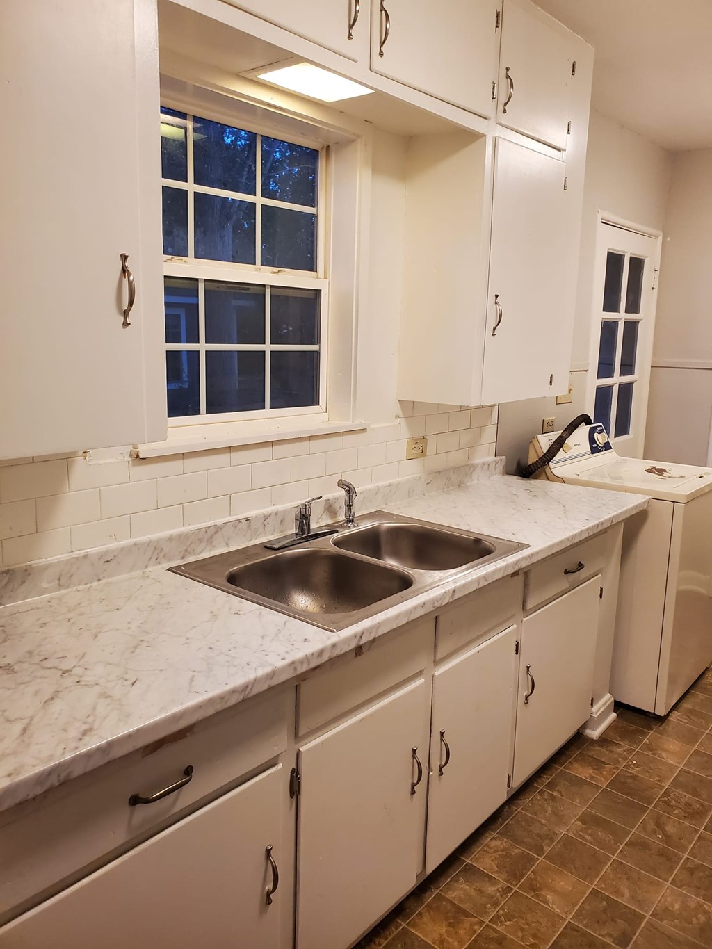 A kitchen with white cabinets and a marble countertop.