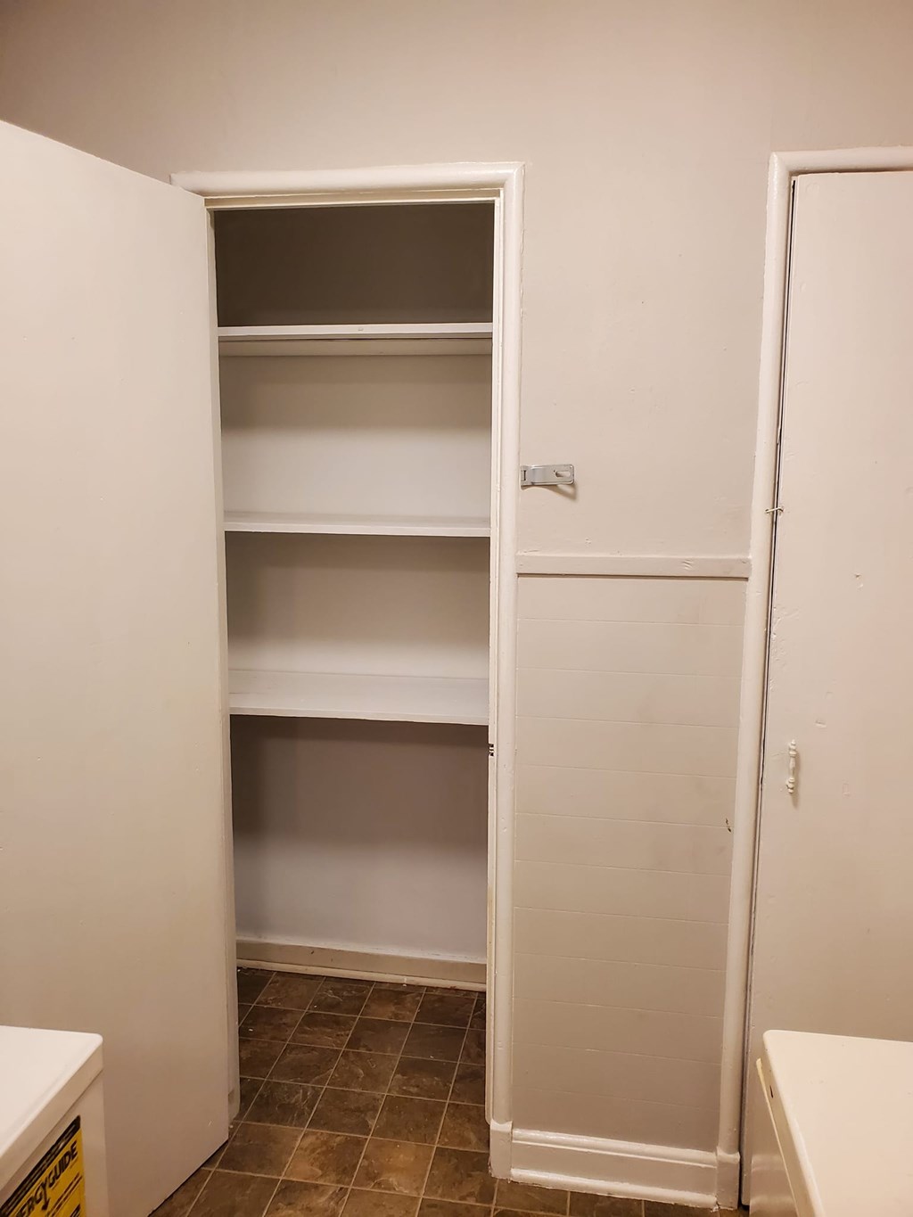 A white closet with shelves and a door open.
