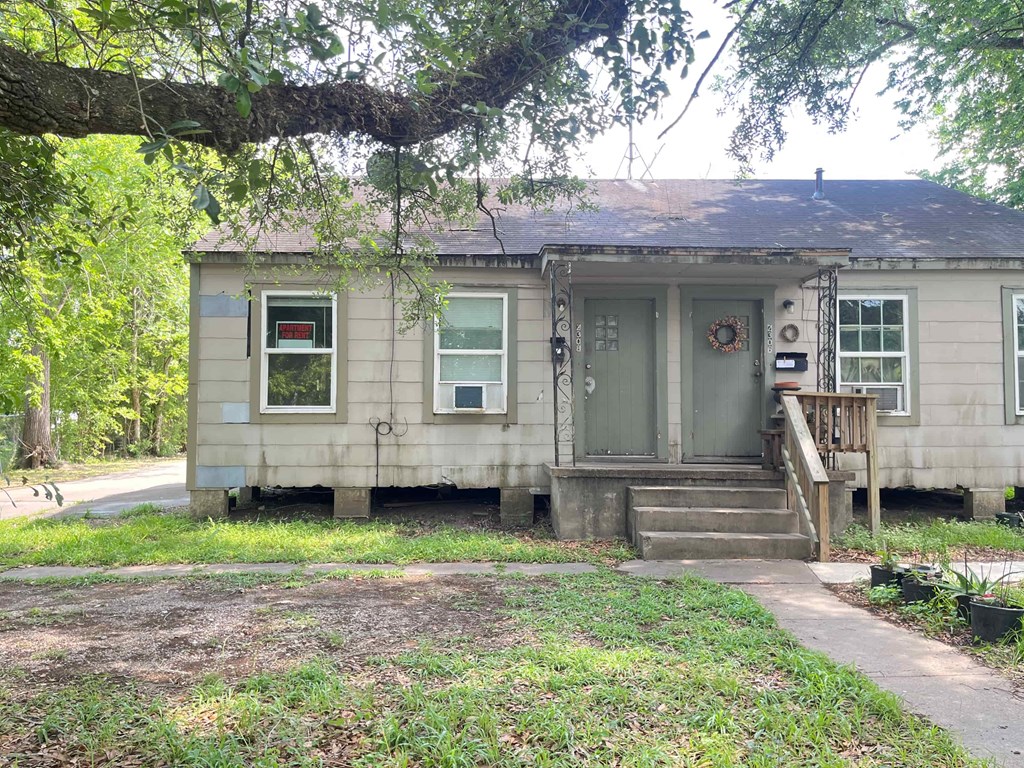 A small, old house with a green door and a porch.