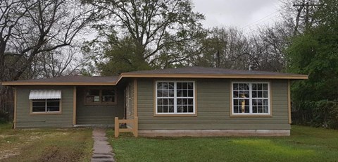 A small house with a brown door and a brown bench in front of it.