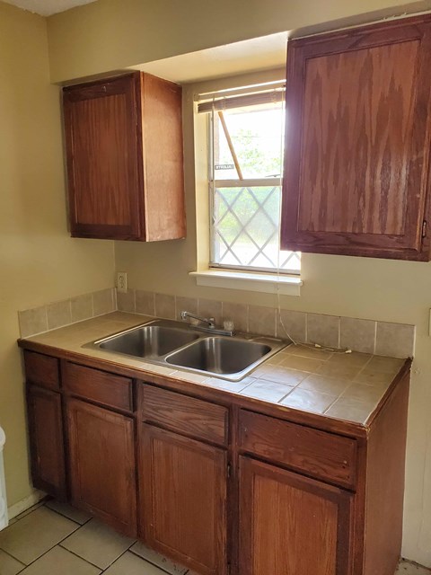 A kitchen with brown cabinets and a window.
