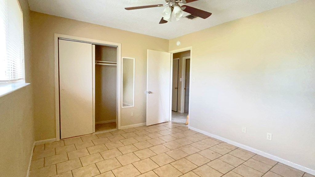 A room with a ceiling fan and tile flooring.