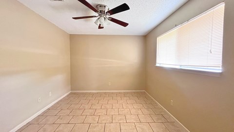 A room with a ceiling fan and a window with blinds.
