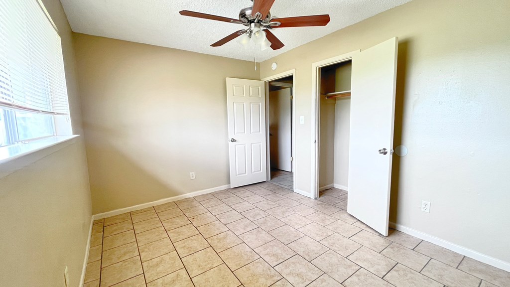A room with a ceiling fan and tile flooring.