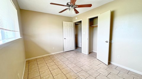 A room with a ceiling fan and tile flooring.