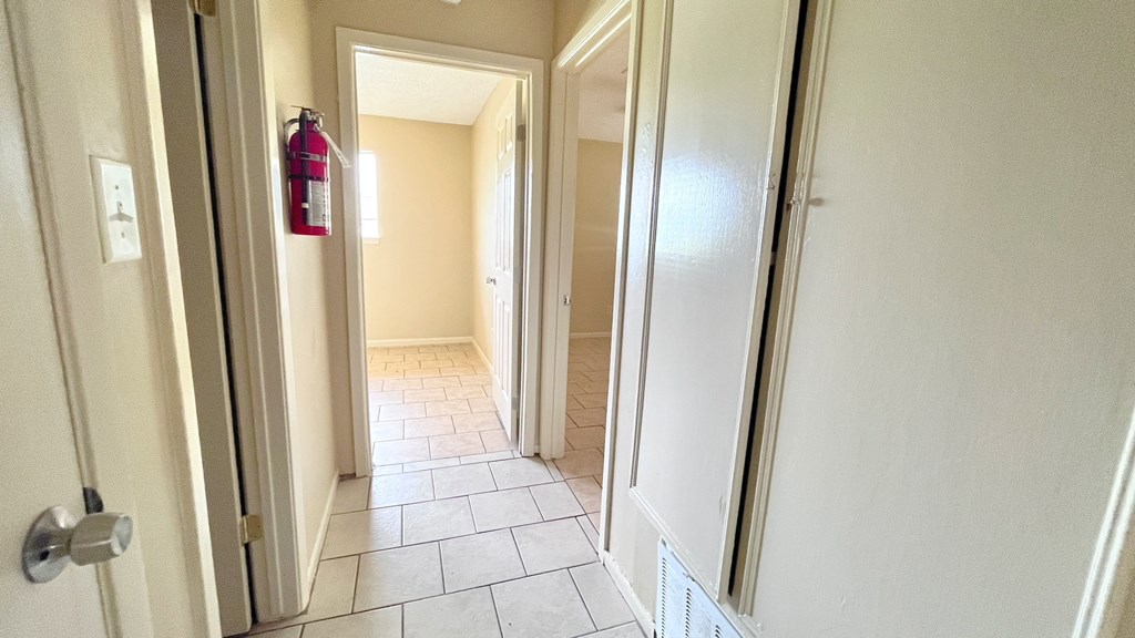 A hallway with a red fire extinguisher hanging on the wall.