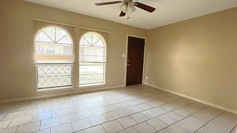 A room with a ceiling fan and two windows.