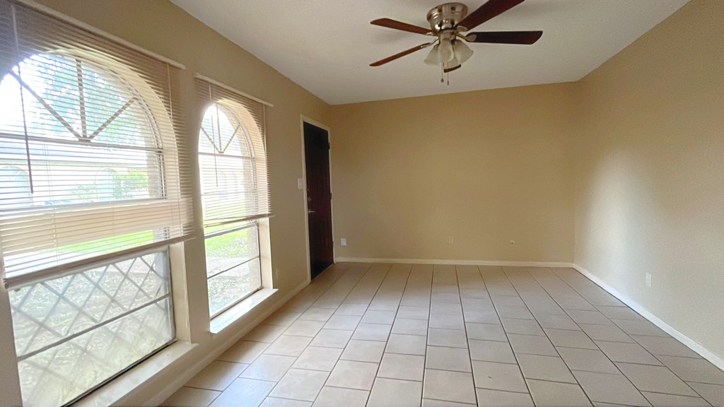 A room with a ceiling fan and tiled flooring.
