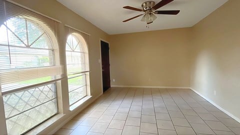 A room with a ceiling fan and tiled flooring.