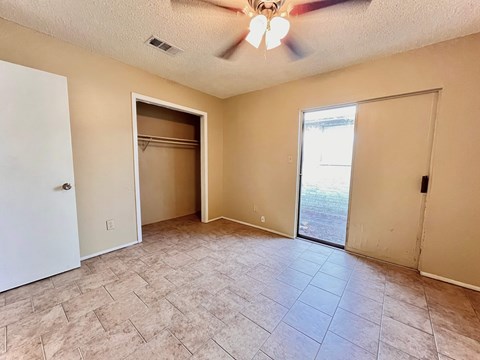 an empty living room with a closet and a ceiling fan