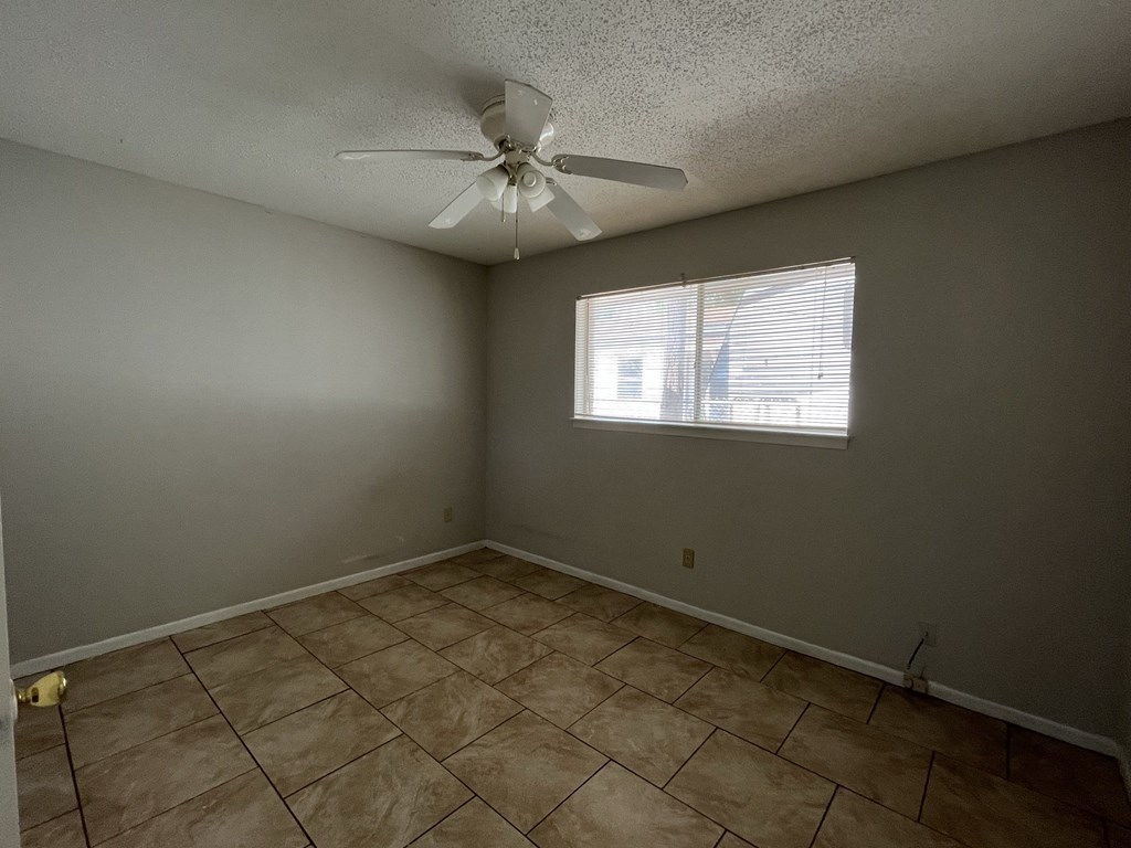 an empty living room with a ceiling fan and a window