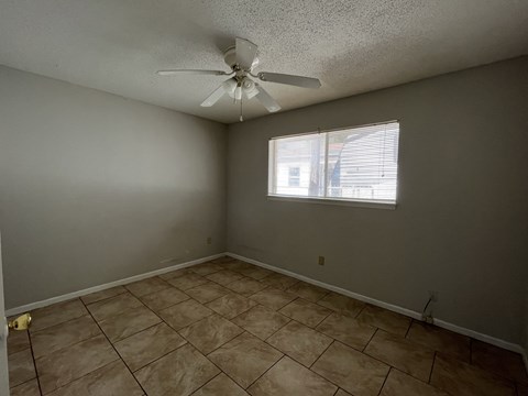 an empty living room with a ceiling fan and a window