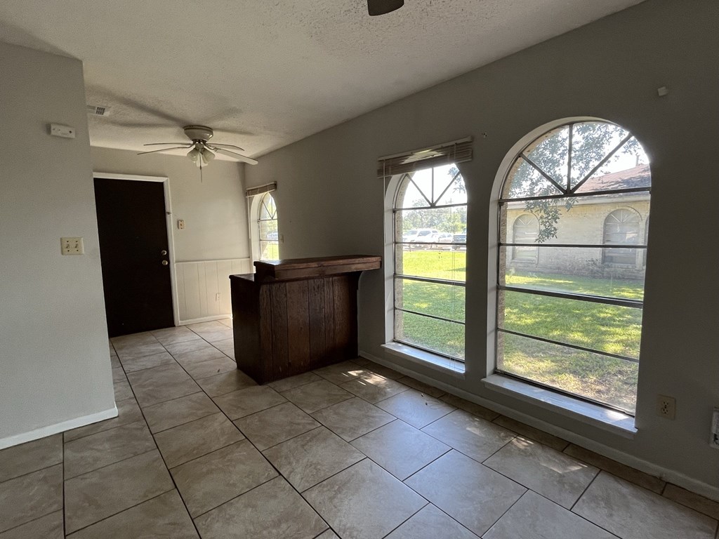 an empty living room with large windows and tiled floors