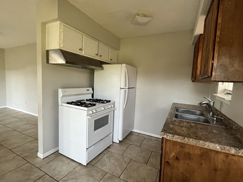 an empty kitchen with a stove refrigerator and sink