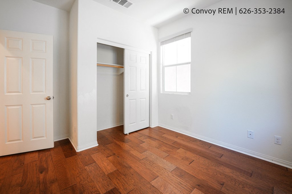 an empty bedroom with wood flooring and a closet