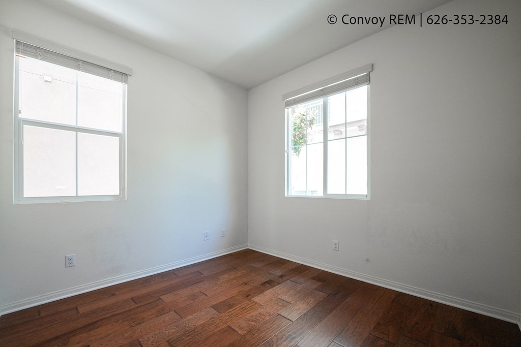 the living room of a house with wood floors and two windows