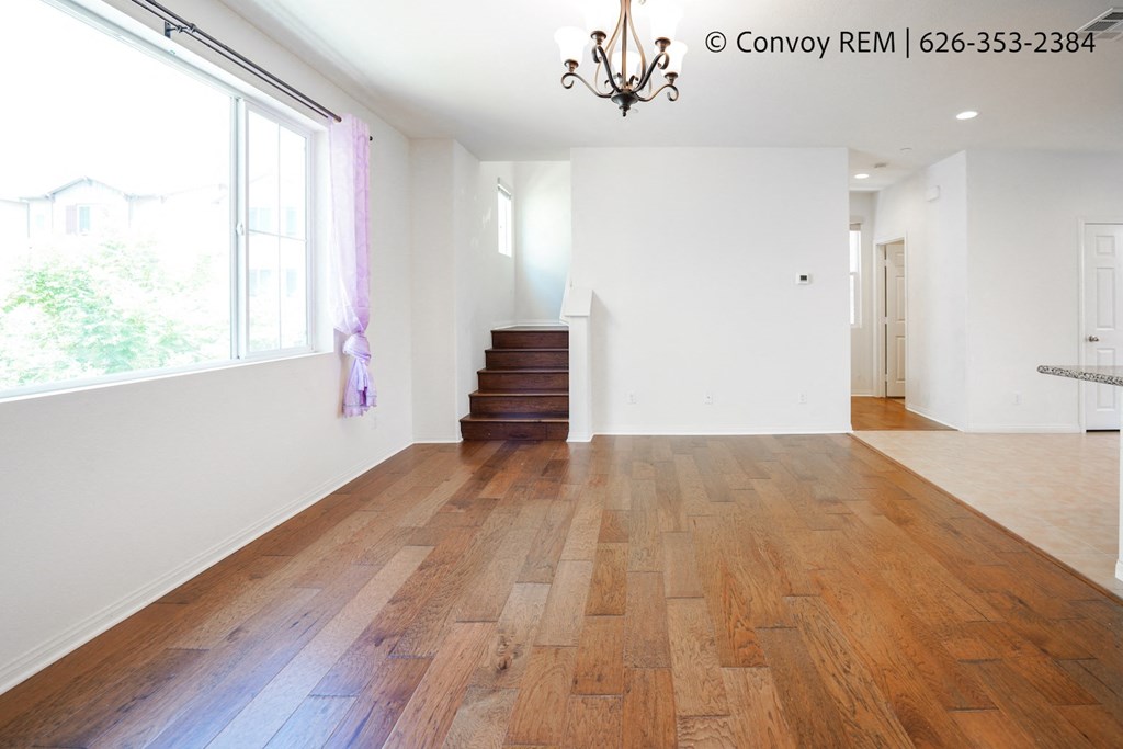 an empty living room with wooden floors and a large window