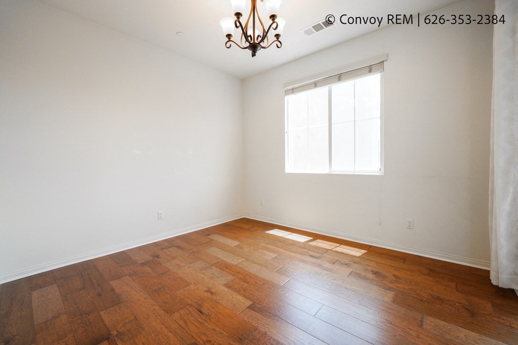 the living room of a home with wood floors and a window