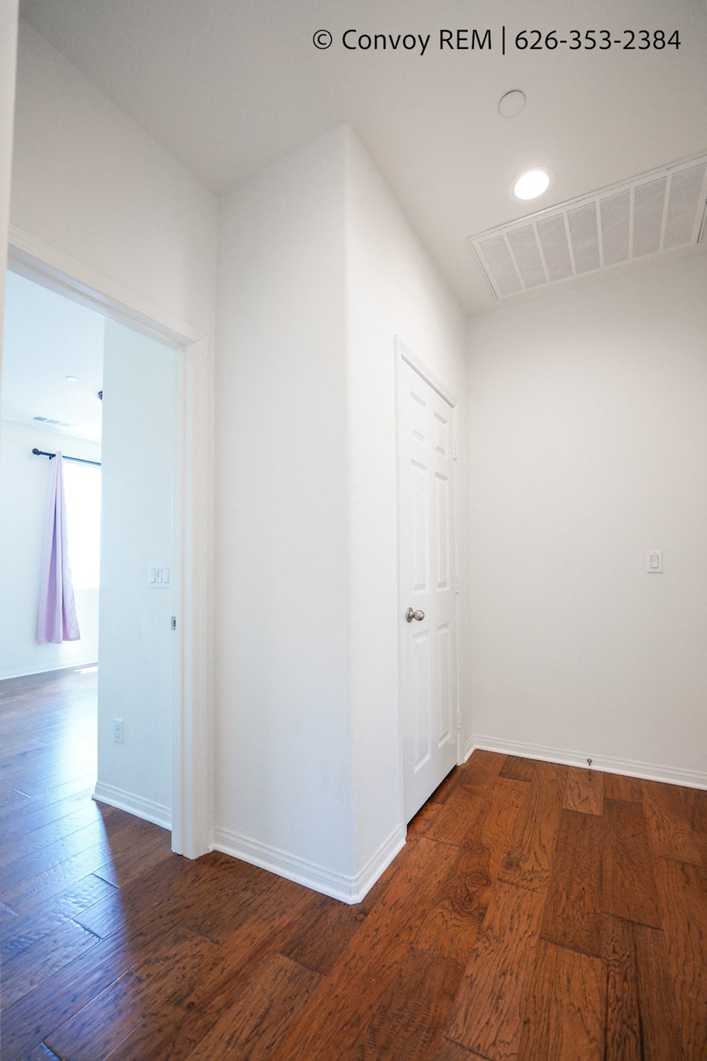 a bedroom with white walls and wood floors and a white door