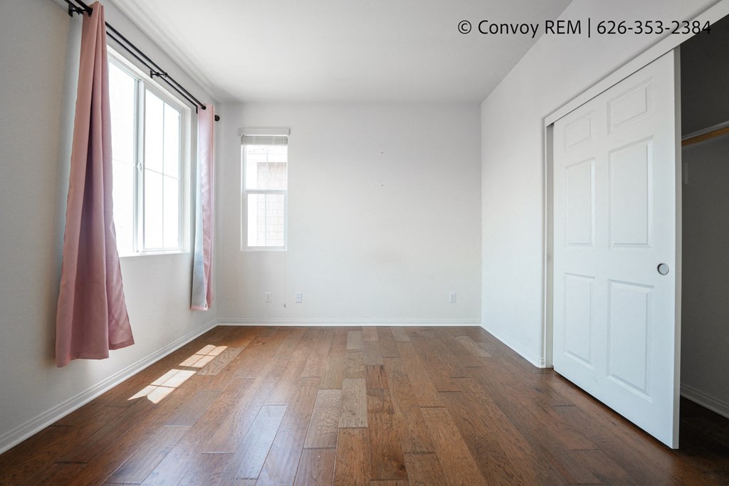 a empty room with wood flooring and a white door and window
