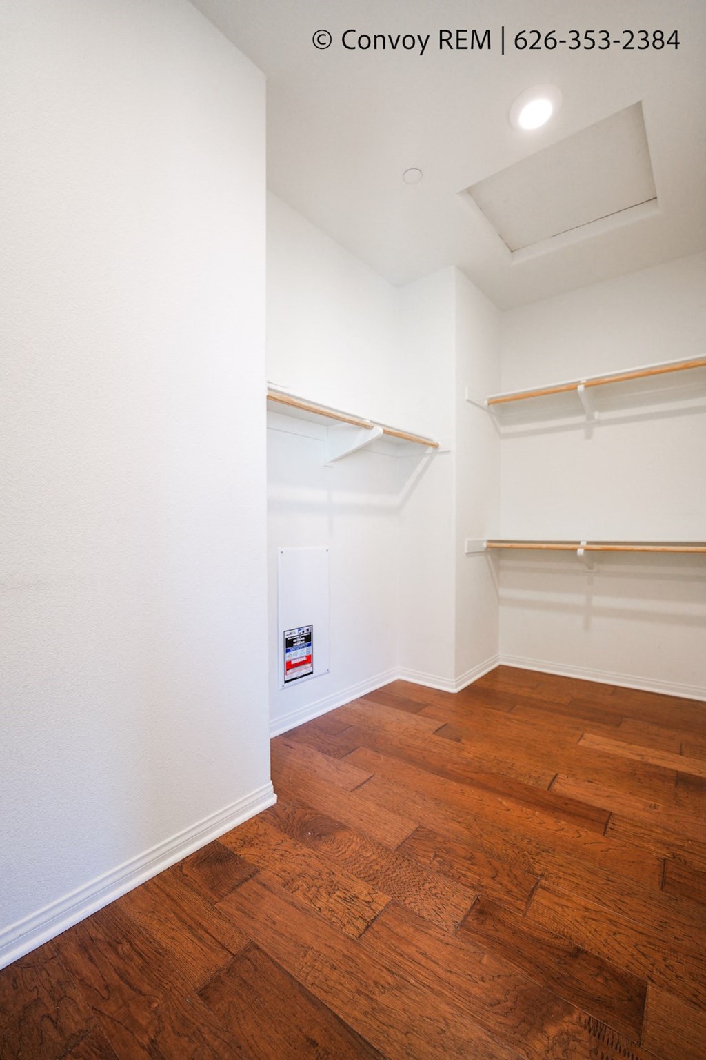 a bedroom with a wood floor and white walls and shelves