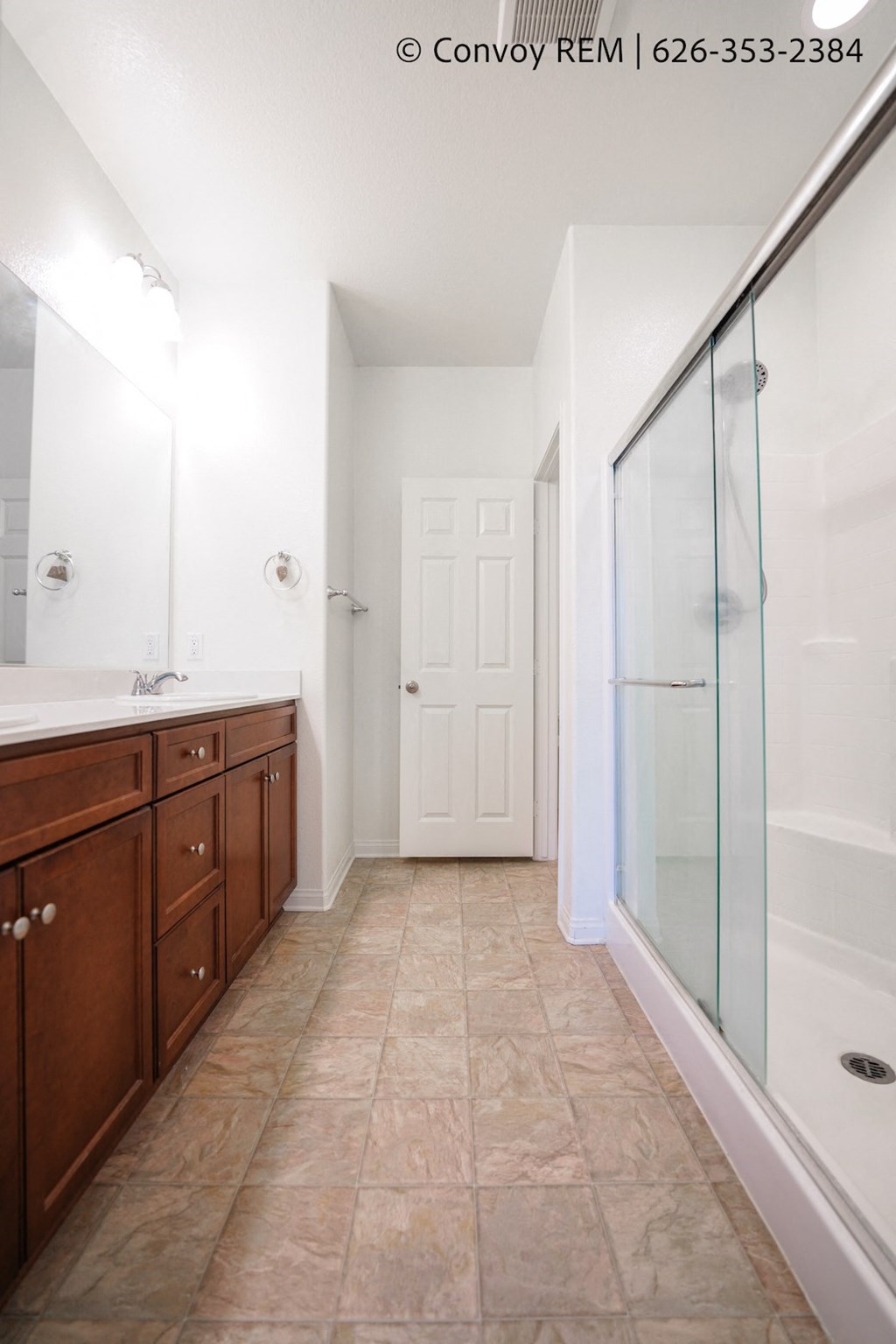 a bathroom with a shower and a sink and wooden cabinets