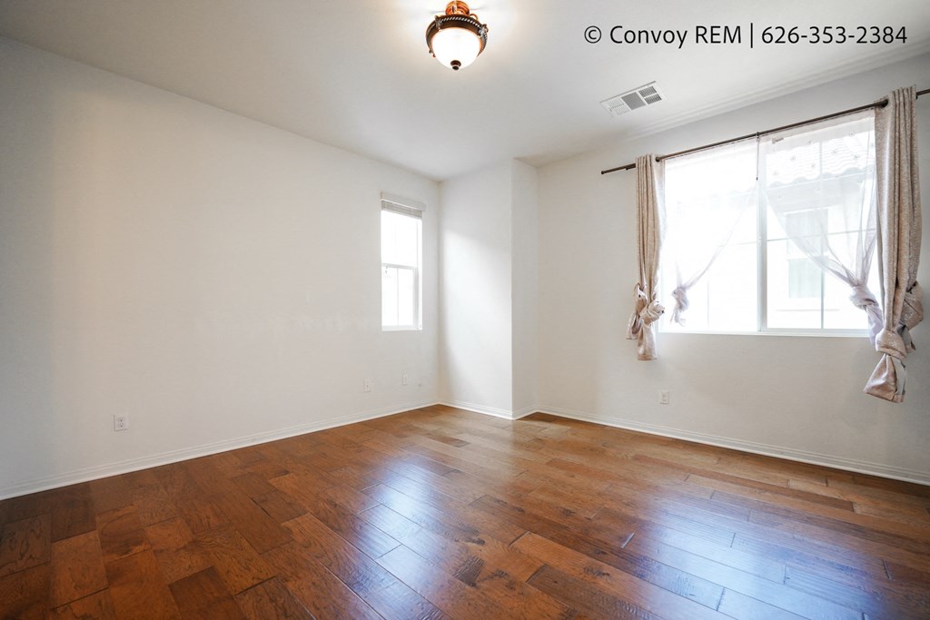 an empty living room with wood floors and a window