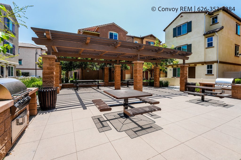 a large patio with picnic tables and a pergola