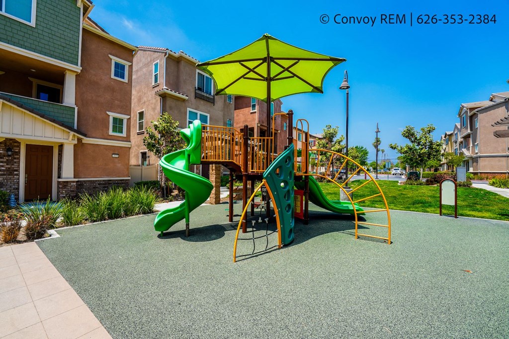 a playground with slides and a umbrella in an apartment complex