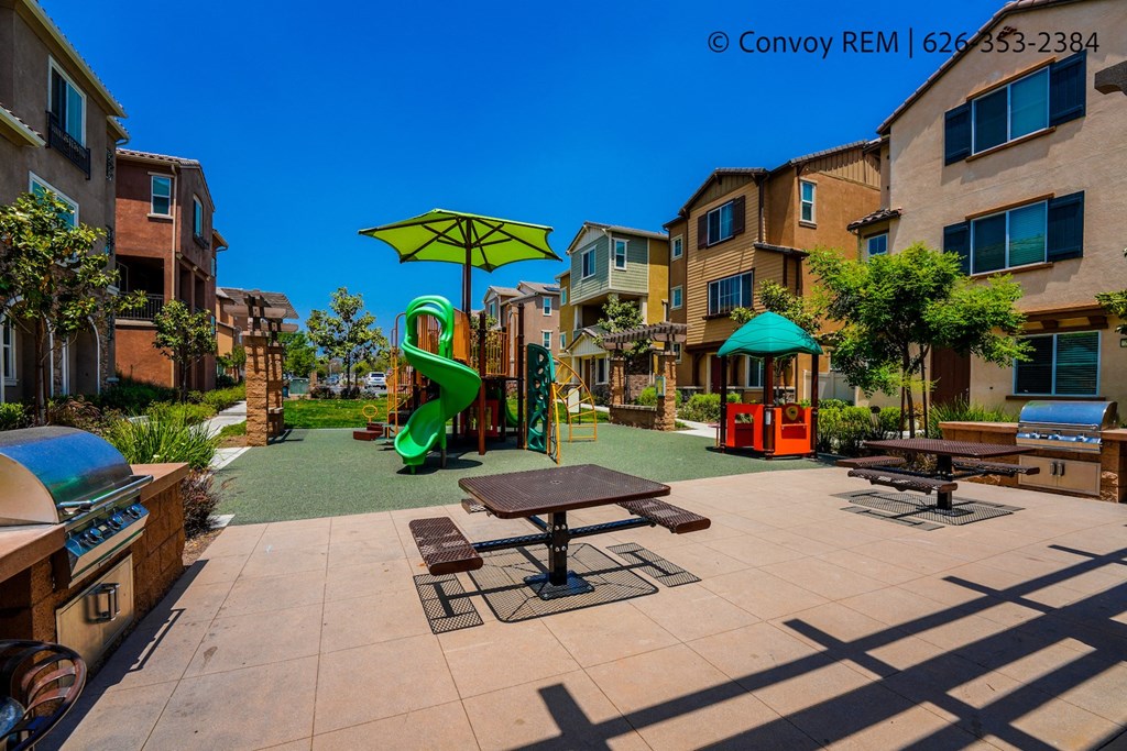 a playground and picnic table in a courtyard of an apartment complex