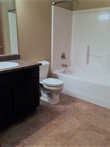 A white toilet sits in a bathroom next to a sink.