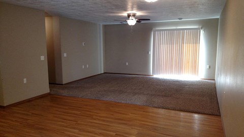A room with a ceiling fan and a rug on the floor.