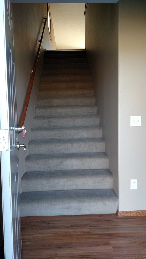 A staircase with a wooden handrail and a white door.