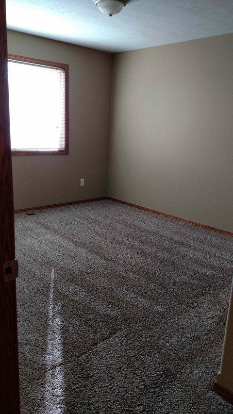 A room with a carpeted floor and a window.
