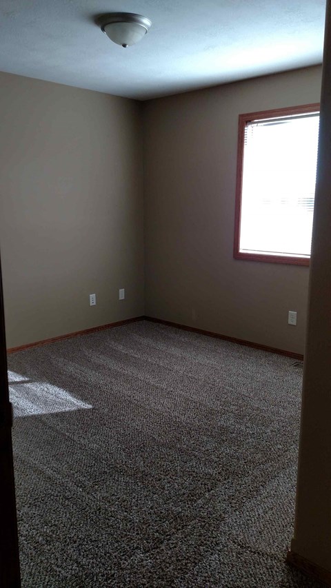 A room with a carpeted floor and a window.