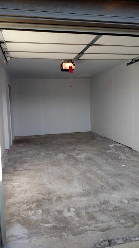 A garage with a concrete floor and a red light hanging from the ceiling.