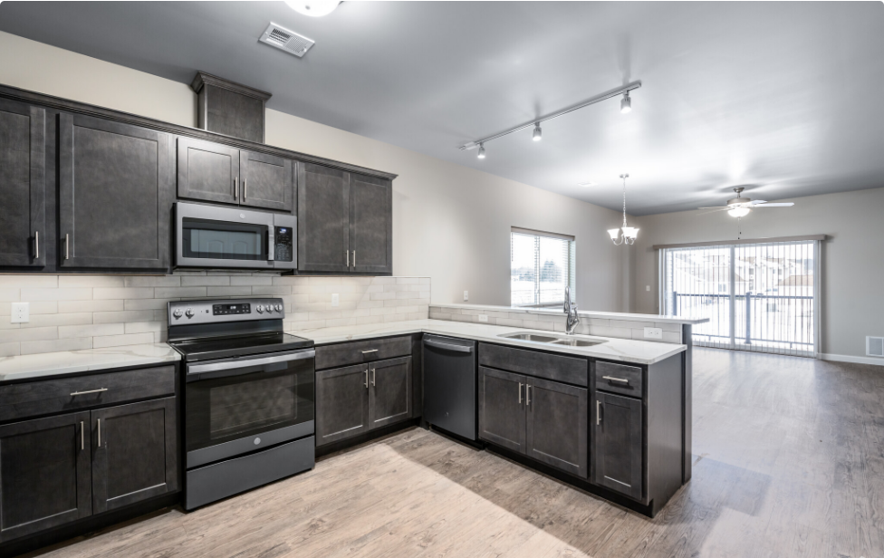 an empty kitchen with dark cabinets and stainless steel appliances