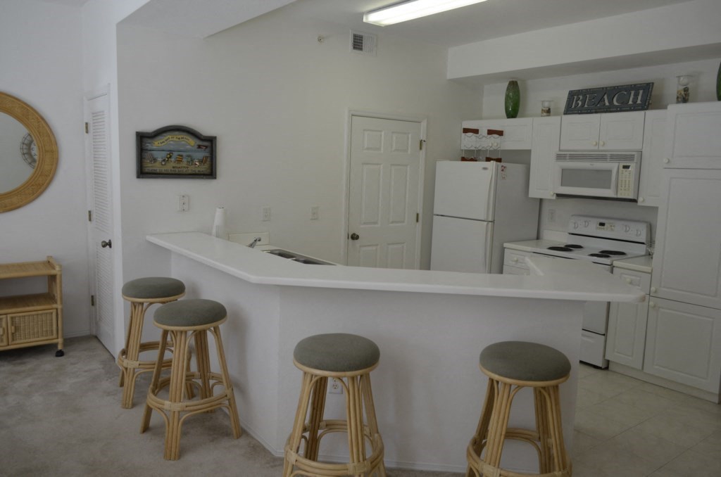 a kitchen with a bar and stools in front of a kitchen counter