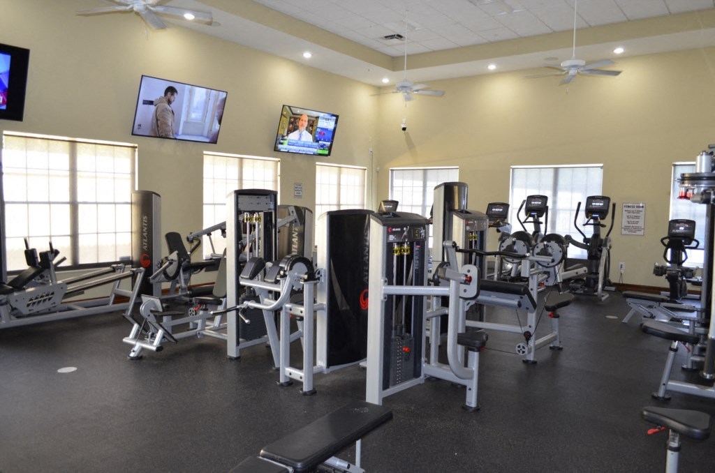 a gym with cardio equipment and a tv on the wall