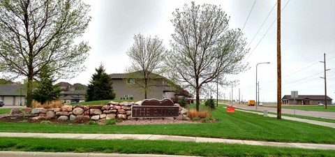 a yard with a stone wall and a sign in front of a house